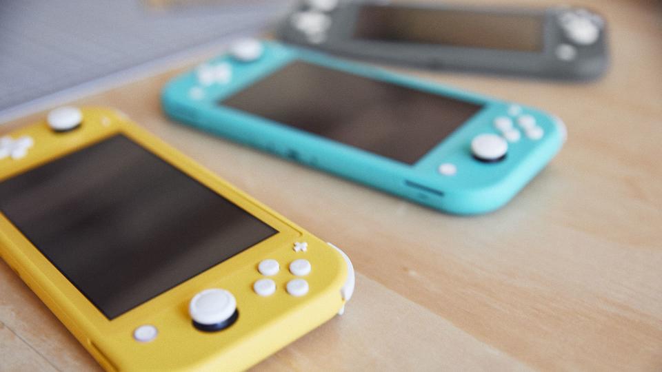 A yellow, blue, and grey Switch Lite laying on a table.