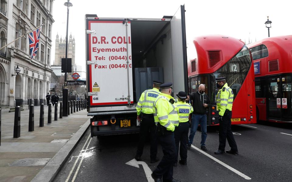 Police speak to a shellfish export truck driver as he is stopped for an unnecessary journey in London - AP