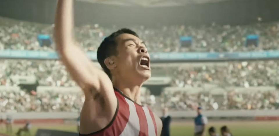 a men cheers in front of a crowded stadium