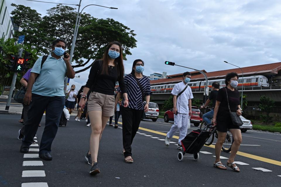 People cross a street in Singapore on June 23, 2020. - Singapore's Prime Minister Lee Hsien Loong called a general election "like no other" on June 23 as the city-state struggles to recover from a major coronavirus outbreak that has swept through crowded migrant worker dormitories. (Photo by Roslan RAHMAN / AFP) (Photo by ROSLAN RAHMAN/AFP via Getty Images)