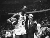 FILE - Bill Russell, left, star of the Boston Celtics is congratulated by coach Arnold "Red" Auerbach after scoring his 10,000th point in the NBA game against the Baltimore Bullets in Boston Garden on Dec. 12, 1964. The NBA great Bill Russell has died at age 88. His family said on social media that Russell died on Sunday, July 31, 2022. Russell anchored a Boston Celtics dynasty that won 11 titles in 13 years. (AP Photo/Bill Chaplis, file)