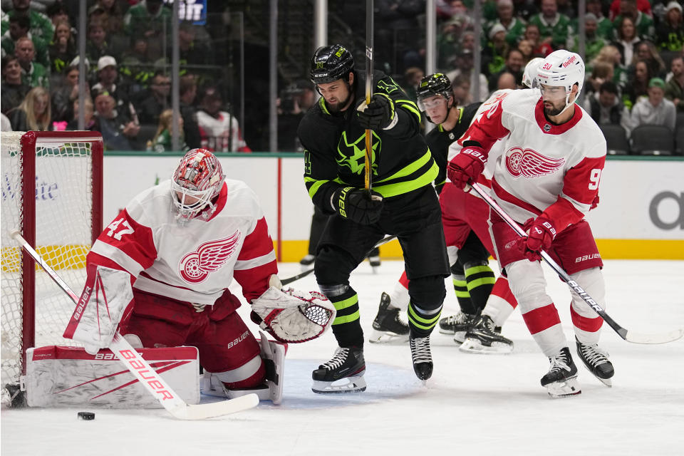 Detroit Red Wings goaltender James Reimer (47) looks down at the puck as center Joe Veleno (90) helps defend the net against pressure from Dallas Stars left wing Jamie Benn (14) in the first period of an NHL hockey game in Dallas, Monday, Dec. 11, 2023. (AP Photo/Tony Gutierrez)