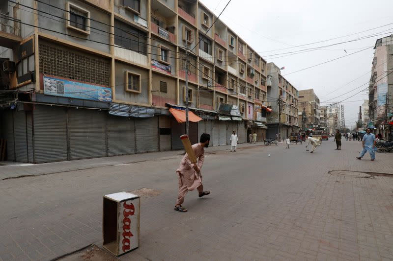 Shopkeepers play cricket along closed market during a partial lockdown amid the outbreak of the coronavirus disease (COVID-19), in Karachi,