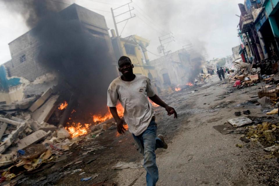 Fleeing: A man runspast a fire in what was downtown Port-au-Prince in 2010 (Marco Dormino/MINUSTAH via Getty Images)