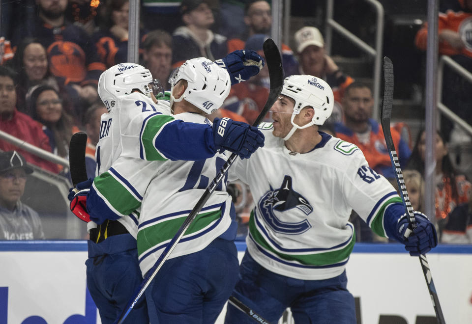 Vancouver Canucks' Nils Hoglander (21), Elias Pettersson (40) and Ian Cole (82) celebrate a goal against the Edmonton Oilers during the first period of an NHL hockey game in Edmonton, Alberta, Saturday, Oct. 14, 2023. (Jason Franson/The Canadian Press via AP)