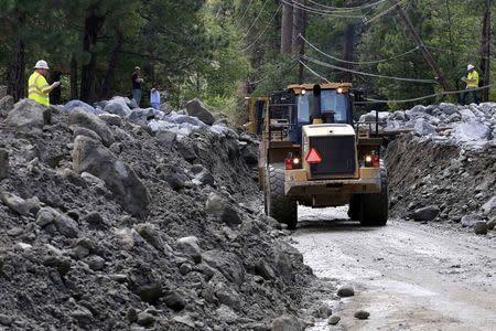 Workers clear a road damaged by a mudflow triggered by flash floods in the San Bernardino National Forest community of Forest Falls, California August 4, 2014. REUTERS/Jonathan Alcorn