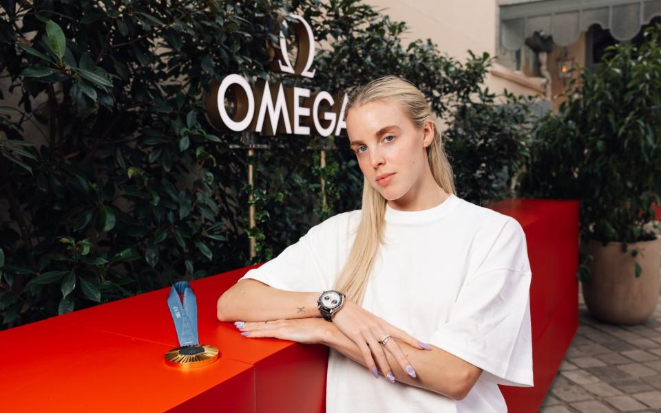 Keely Hodgkinson poses with her gold medal with an Omega watches logo in the background