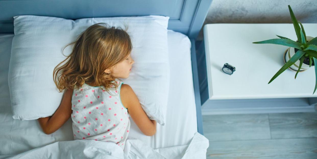 little girl sleeping on a big and cozy bed white linen in the afternoon at home