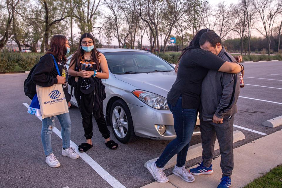 From left, Gabby and Alexis Burnett talk as Anna and Mike Burnett hug after receiving a donated vehicle and laptop from Dirk Heinen on Dec. 9, 2021. The car has made a huge difference in the family's life.