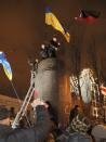 Ukrainian protesters put up Ukrainian flags in place of the ruined monument to Vladimir Lenin in central Kiev, Ukraine, Sunday, Dec. 8, 2013. Anti-government protesters have toppled the statue of Bolshevik leader Vladimir Lenin in central Kiev amid huge protests gripping Ukraine. A group of protesters dragged down and decapitated the landmark statue Sunday evening after hundreds of thousands of others took to the streets to denounce the government's move away from Europe and toward Moscow. (AP Photo/Efrem Lukatsky)