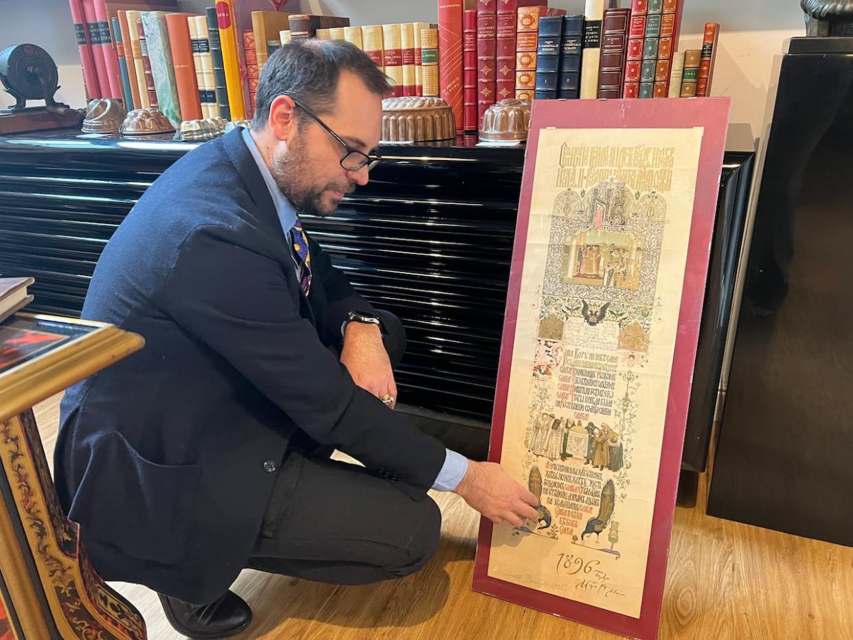 Matteo Ghirighini, director of the Garum Library and Museum of Cuisine, points out a detail in the menu for the coronation of the last czar of Russia. (Megan Williams/CBC - image credit)