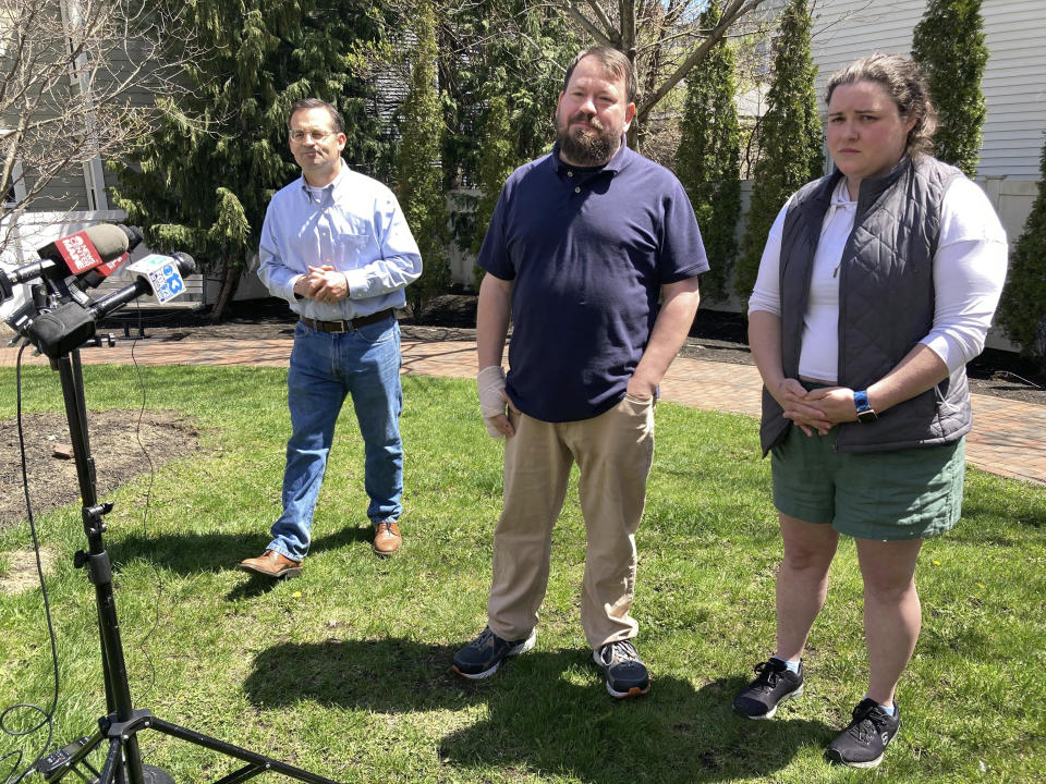 Sean Halsey, center, who was injured along with his children (not shown) in a shooting in Maine last week, speaks at a news conference outside Maine Medical Center in Portland, Maine, Friday, April 28, 2023. Family friends Seth Berry, left, and Haley Murphy, right, joined him. Halsey said he and his children are recovering from their injuries and grateful for the support they've received from the community. A 34-year-old man confessed last week to four killings at a home in Bowdoin and injuring the three people while shooting at vehicles on Interstate 295 in Yarmouth, police have said. (AP Photo/Patrick Whittle)