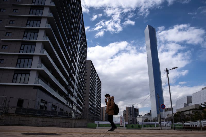 A man wearing a face mask, following an outbreak of the coronavirus, walks past an under-construction site of the Tokyo 2020 Olympics villages in Tokyo