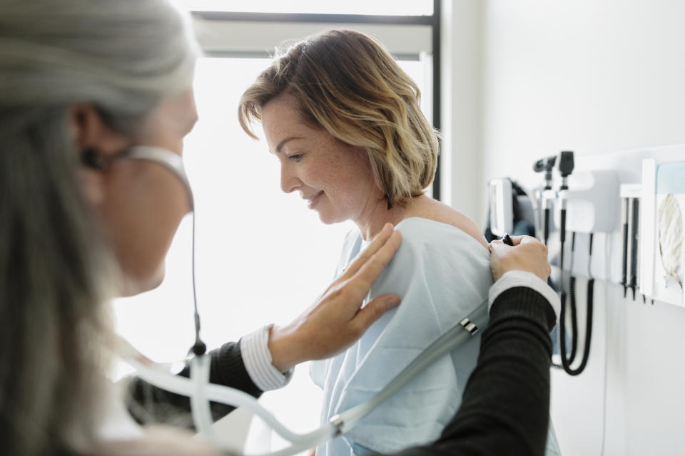 Female doctor with stethoscope examining woman in clinic examination room