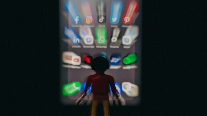 a dark figure in front of a blurred smartphone screen