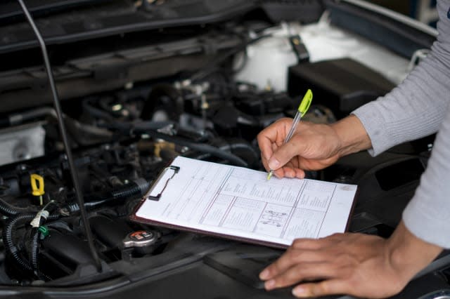 Auto mechanic (or technician) checking car engine at the garage