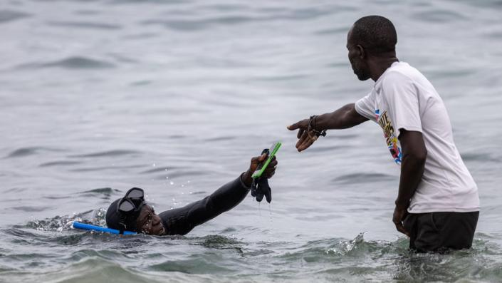 An ocean diver hands over a phone to another man on 24 July 2023