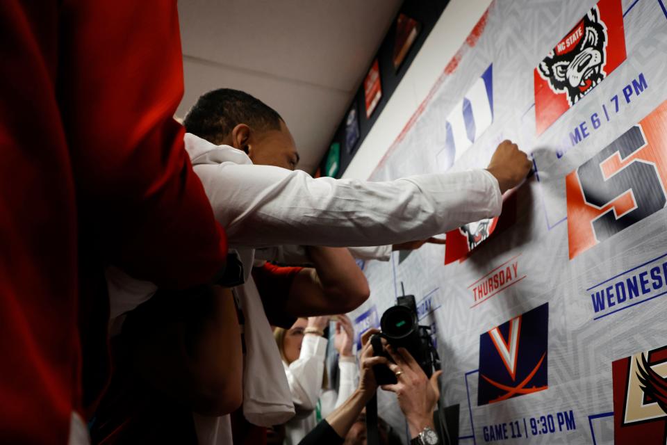 North Carolina State's KJ Keatts places the team sticker on the tournament bracket banner after their ACC tournament game against Syracuse on March 13, 2024.