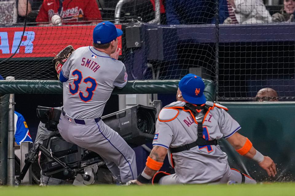 New York Mets relief pitcher Drew Smith (33) slides into the tv camera well trying to catch a foul ball against the Atlanta Braves during the eighth inning on April 8, 2024, at Truist Park.