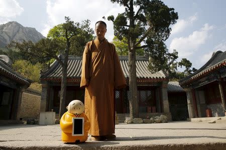 Master Xianfan looks at robot monk Xian'er as he prepares to pose for photograph in the main building of Longquan Buddhist temple on the outskirts of Beijing, April 20, 2016. REUTERS/Kim Kyung-Hoon