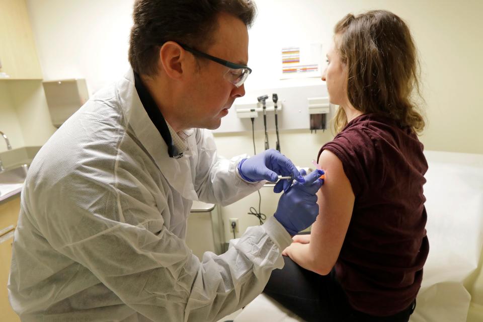 Pharmacist Michael Witte, left, gives Rebecca Sirull, right, the shot.