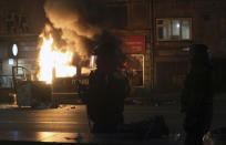 Riot police officers stand by a burning police van as Bulgarian fans clash with police during the Euro 2024 Bulgaria v Hungary soccer match, played at closed doors, in Sofia, Thursday, Nov. 16, 2023. Thousands of Bulgarian football supporters have taken to the streets of the capital, Sofia, in protest over the management of the national football union, a demonstration that eventually turned violent. The European soccer qualifier between Bulgaria and Hungary fell victim to a bitter dispute between the management of the Bulgarian Football Union and soccer fans from across the Balkan country. (AP Photo/Valentina Petrova)