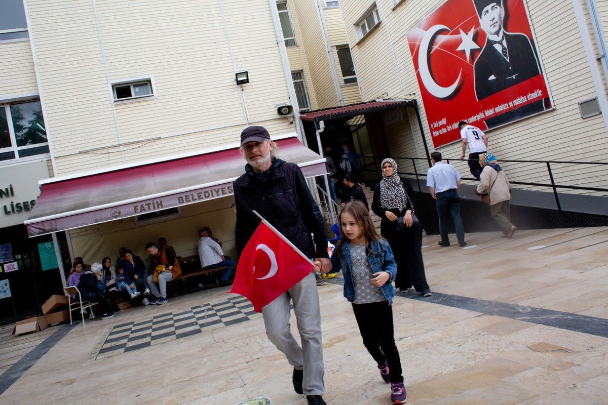 A voter and a child emerge from a polling station in Istanbul (Yusuf Sayman/For The Independent)