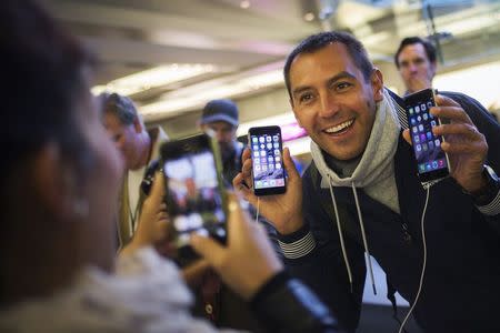 Michele Mattana of Sardinia, Italy, poses with an iPhone 6 Plus and an iPhone 6 on the first day of sales at the Fifth Avenue store in Manhattan, New York September 19, 2014. REUTERS/Adrees Latif