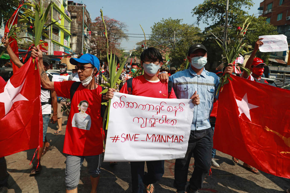 A protester holds a banner that says "Save Myanmar" as they march in Yangon, Myanmar on Sunday, Feb. 7, 2021. Thousands of people rallied against the military takeover in Myanmar's biggest city on Sunday and demanded the release of Aung San Suu Kyi, whose elected government was toppled by the army that also imposed an internet blackout. (AP Photo)