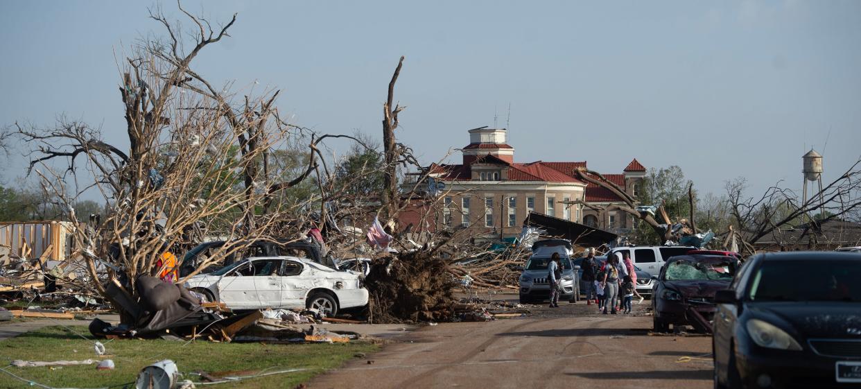 March 25, 2023 — With the heavily damaged Sharkey County Courthouse in Rolling Fork, in the background, people walk down what is left of a decimated Worthington Avenue Saturday, March 25, 2023, after a tornado ripped through the small Delta town Friday night. (Clarion Ledger/File photo)