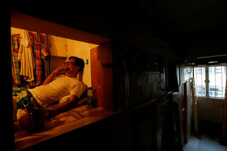 Unemployed Hong Kong resident Simon Wong, 61, smokes inside his 4-by-6-feet partitioned unit, or "coffin unit", with a monthly rent of HK$1,750 ($226) in Hong Kong, China October 31, 2016. REUTERS/Bobby Yip