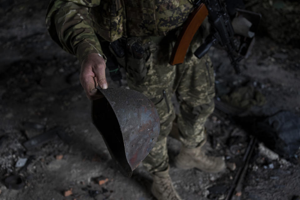 A Ukrainian serviceman holds the helmet used by Russian troops inside a school damaged during a battle between Russian and Ukrainian forces in the village of Vilkhivka, on the outskirts of Kharkiv, in eastern Ukraine, Friday, May 20, 2022. (AP Photo/Bernat Armangue)