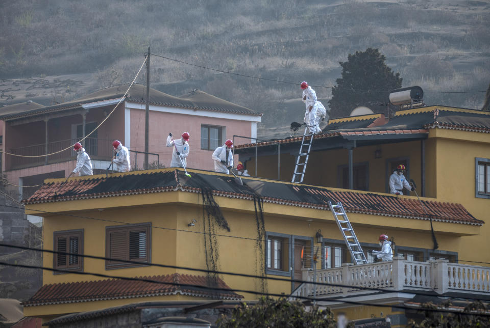 Military personnel clean up the ash off a house from the volcano in Las Manchas on the Canary island of La Palma, Spain on Thursday Oct. 14, 2021. Hundreds of people in Spain's Canary Islands are fearing for their homes and property after a new lava stream from an erupting volcano threatened to engulf another neighborhood on the island of La Palma. (AP Photo/Saul Santos)