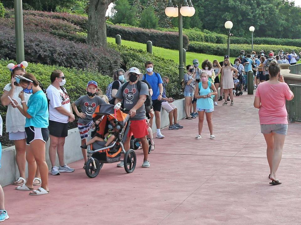 Guests wearing protective masks wait to pick up their tickets at the Magic Kingdom theme park at Walt Disney World on the first day of reopening, in Orlando, Florida, on July 11, 2020: Gregg Newton/AFP via Getty Image