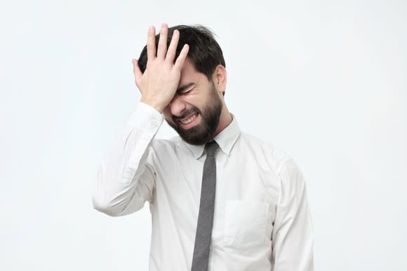 Man in shirt and tie smacking his head.