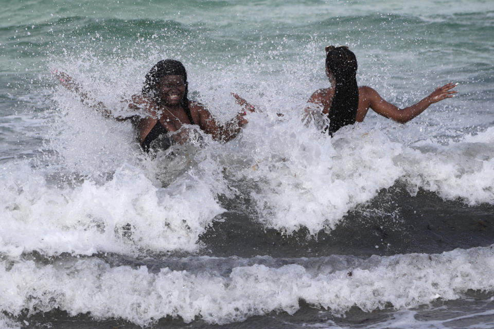 Women enjoy the waves from a high surf, Friday, July 31, 2020, in Miami Beach, Fla. Forecasters declared a hurricane warning for parts of the Florida coast Friday as Hurricane Isaias drenched the Bahamas on track for the U.S. East Coast. (AP Photo/Lynne Sladky)