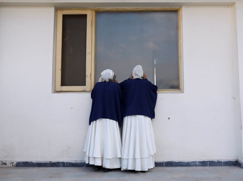 Members of a Sama Dance group look through the window before dancing in Kabul