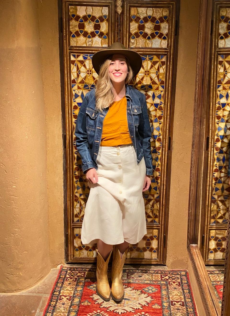 A woman posing with a cowboy hat and cowboy boots