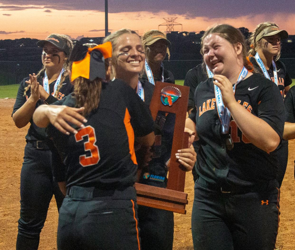 Lake Wales senior Kylie Granger hugs Jaley Rodriguez (3) as Lexi Thomas looks on after the three seniors accept the runner-up trophy on Friday.