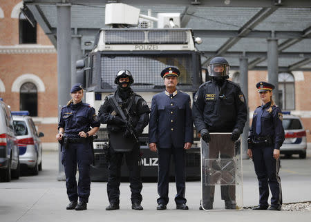 Austrian police officers pose in various uniforms in front of a water cannon at their headquarters in Vienna October 8, 2014. REUTERS/Leonhard Foeger