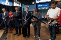 From left, Caesars Sports & Online Gaming Co-President Eric Hession, CEO of Caesars Entertainment CEO Tom Reeg, Monumental Sports & Entertainment Business Operations & Chief Commercial Officer President Jim Van Stone, Founder & CEO of Monumental Sports & Entertainment and owner of the Washington Wizards and the Washington Capitals Ted Leonsis, and chef Nicholas Stefanelli participate in a ribbon cutting for the William Hill Sportsbook at Monumental Sports & Entertainment's Capital One Arena in Washington, Wednesday, May 26, 2021. The William Hill Sportsbook is the first ever sports betting venue to open within a U.S. professional sports facility. (AP Photo/Andrew Harnik)