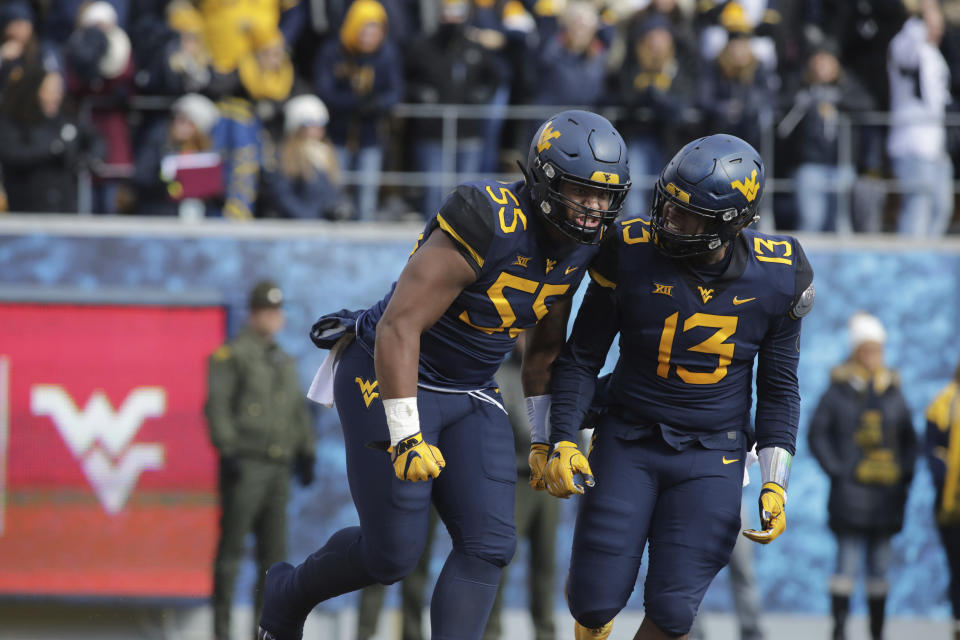 West Virginia linebacker Dante Stills (55) and defensive lineman Jeffery Pooler Jr. (13) celebrate a defensive stop during the first half of an NCAA college football game against TCU Saturday, Nov. 10, 2018, in Morgantown, W.Va. (AP Photo/Raymond Thompson)