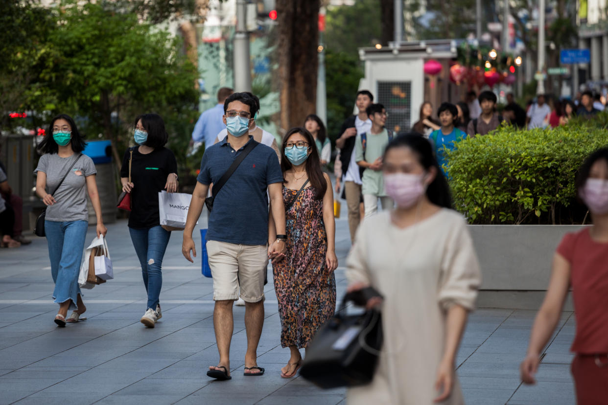 People wearing protective face masks walks along Orchard Road on 14 February, 2020. (PHOTO: LightRocket via Getty Images)