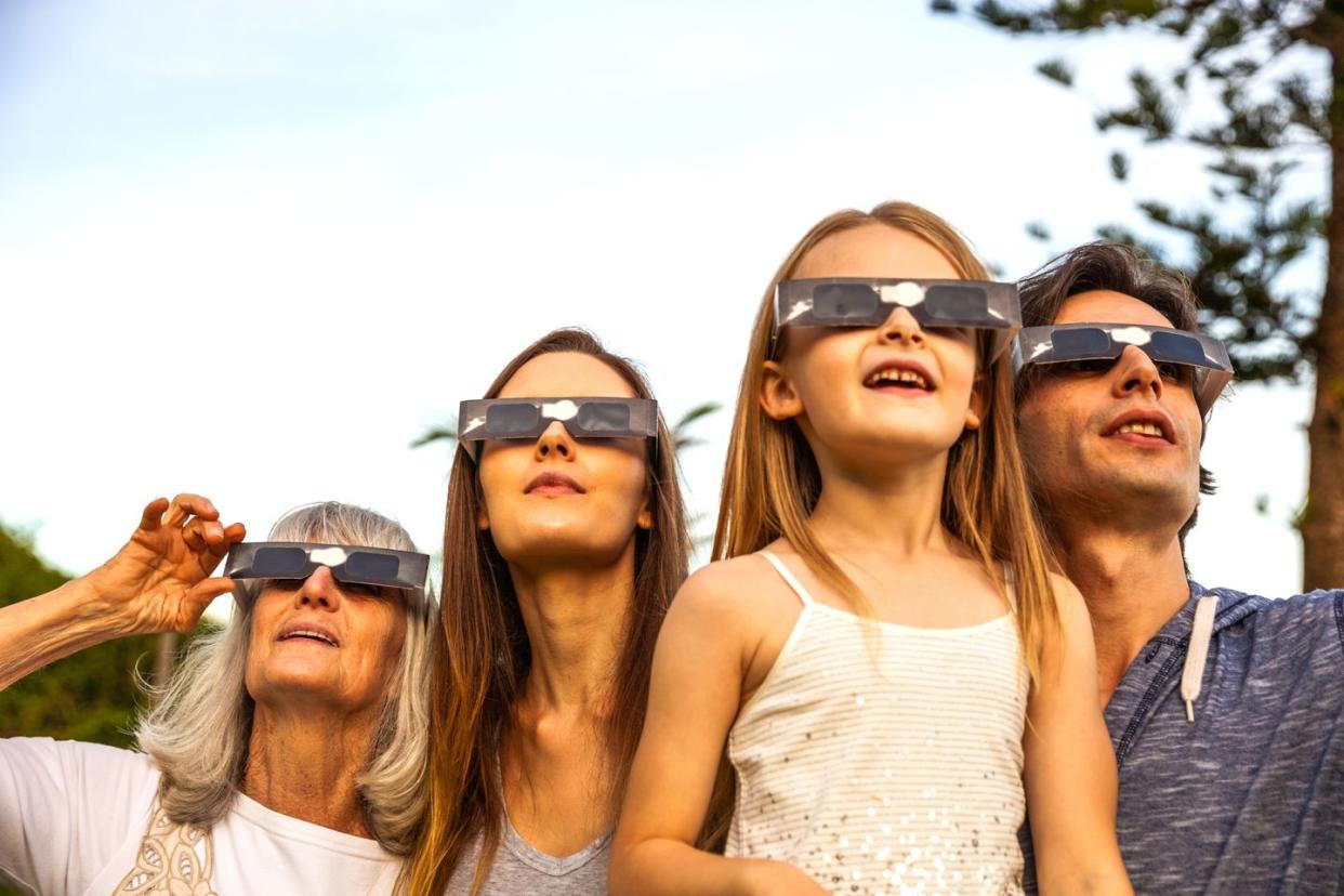 family looking at solar eclipse using solar glasses