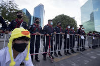 /// A protester wearing a headgear designed as a yellow duck, which has become a good-humored symbol of resistance during anti-government rallies, sits in front of police standing guard outside the Siam Commercial Bank Wednesday, Nov. 25, 2020 in Bangkok, Thailand. Thai authorities have escalated their legal battle against the students leading pro-democracy protests, charging 12 of them with violating a harsh law against defaming the monarchy. (AP Photo/Wason Wanichakorn)