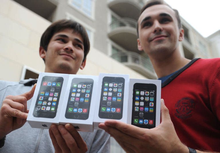 Two men display their four new iPhone 5S outside the Apple Store in Glendale, California, September 20, 2013