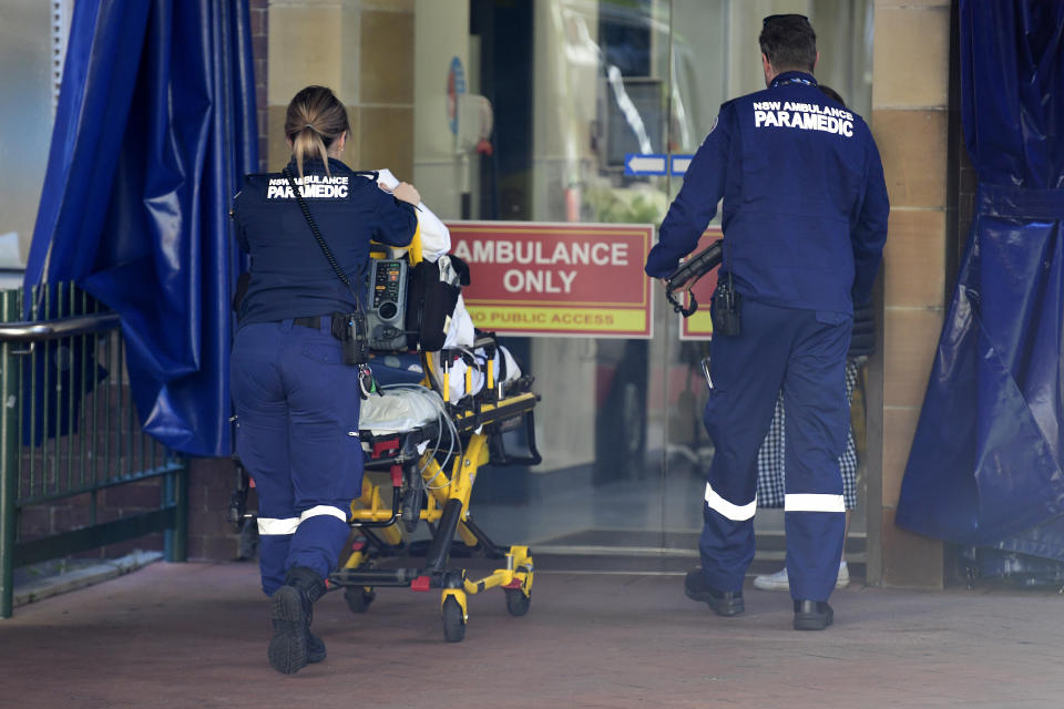 Two paramedics are seen pushing a patient into the hospital. 