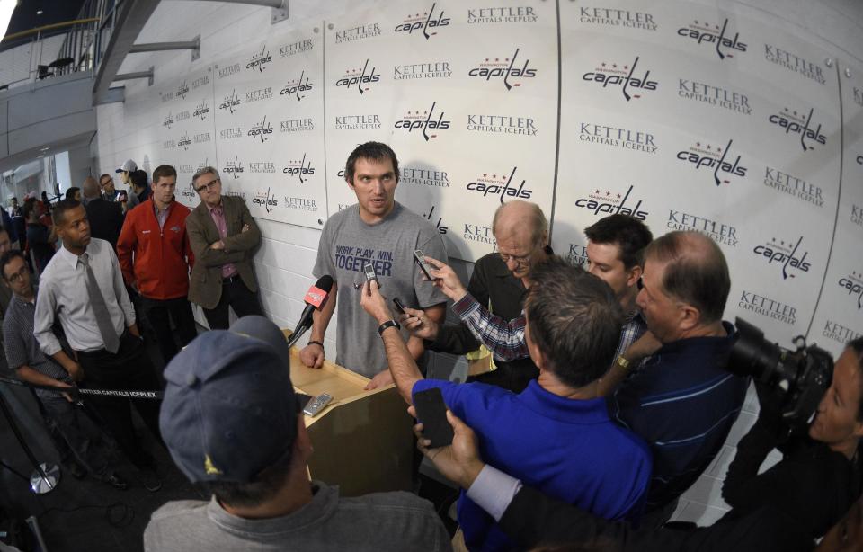 In this image taken with a fisheye lens, Washington Capitals' Alex Ovechkin, of Russia, center, talks with the media during NHL hockey training camp, Friday, Sept. 19, 2014, in Arlington, Va. (AP Photo/Nick Wass)