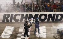 Martin Truex Jr. holds the checkered flag after winning the NASCAR Cup Series auto race at Richmond Raceway in Richmond, Va., Saturday, April 13, 2019. (AP Photo/Steve Helber)