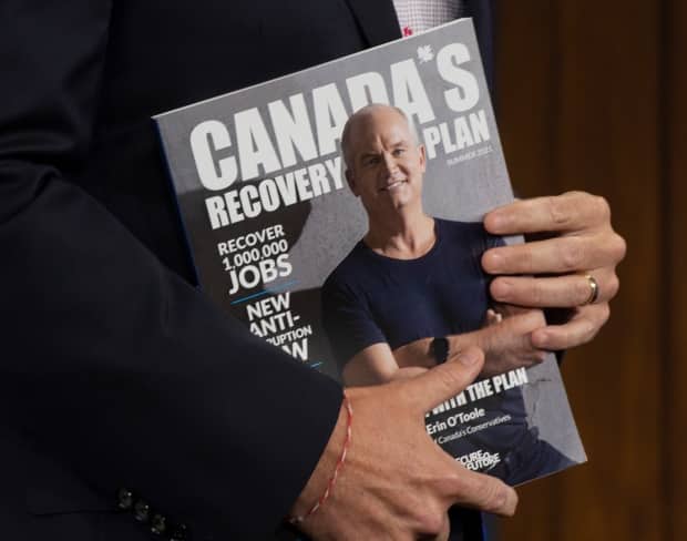 Conservative Leader Erin O'Toole holds a copy of his party's recovery plan as he campaigns in August in Ottawa. The federal election is Sept. 20. (Ryan Remiorz/The Canadian Press - image credit)